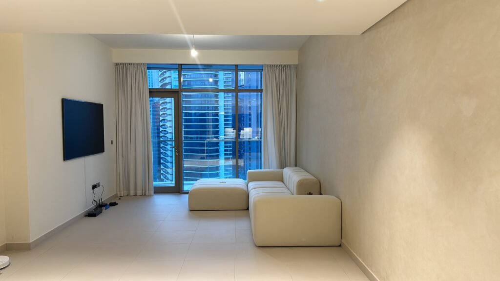Modern UAE apartment living room featuring large floor-to-ceiling smart glass windows overlooking Dubai's skyline, designed for natural light, energy efficiency, and contemporary living.